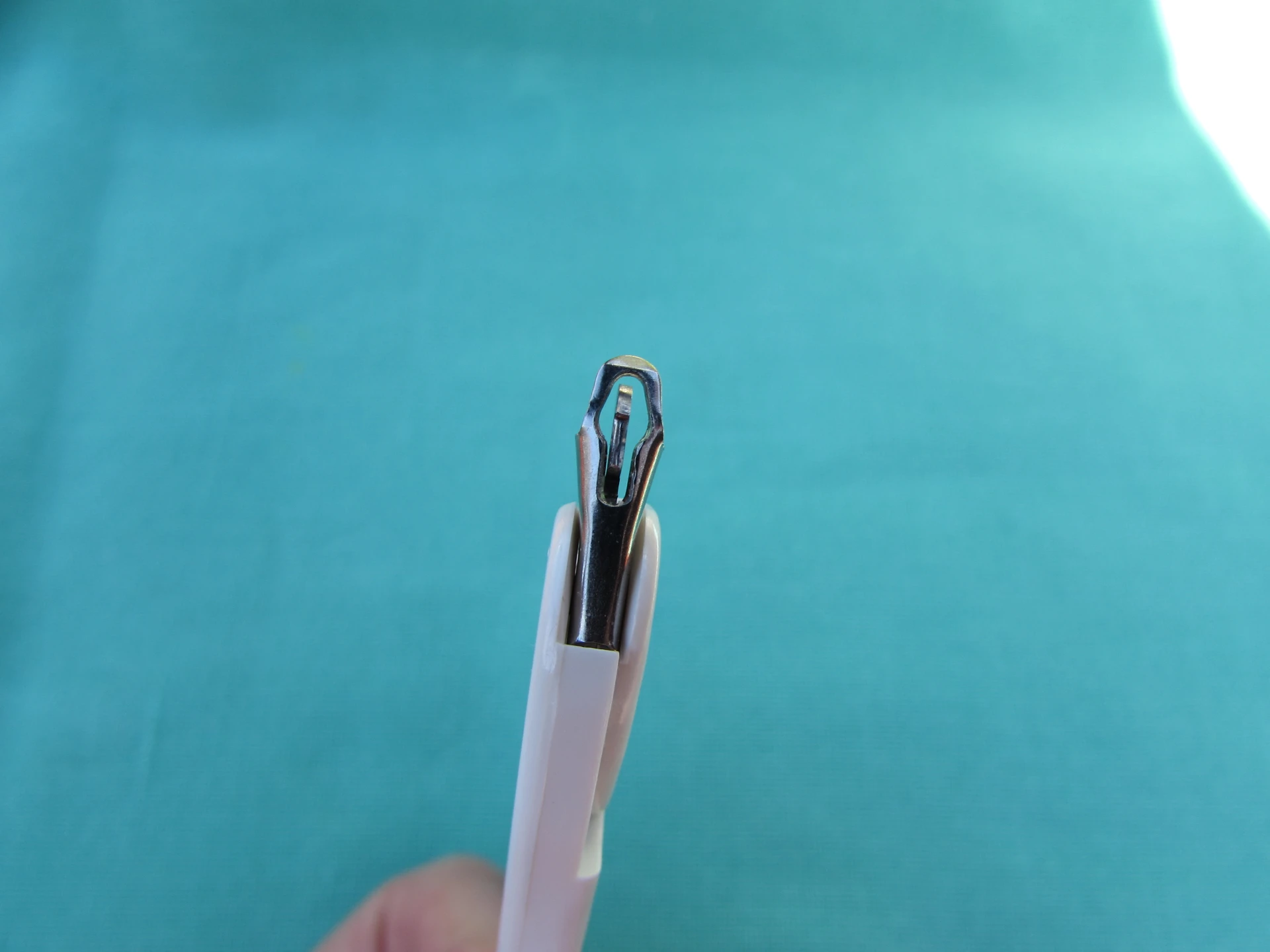 Disposable surgical skin-clip (staple) remover, close-up showing lower-jaw geometry that seats under the staple center