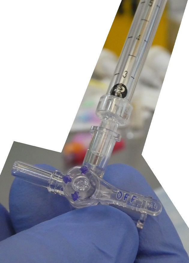 Three-way stopcock attached to spinal manometer with directional flow arrows